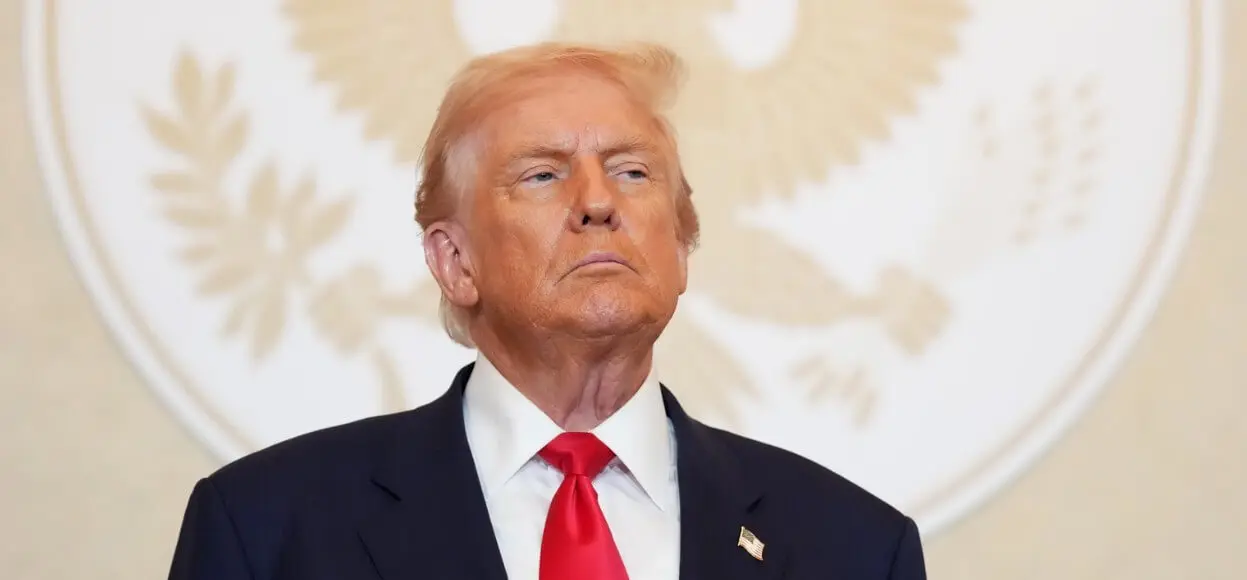 Man in suit red tie before presidential seal