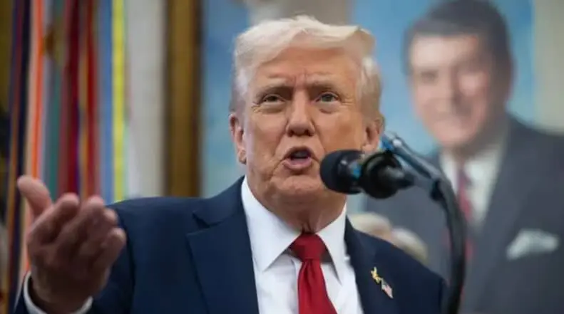 Man gesturing while speaking at microphone indoors
