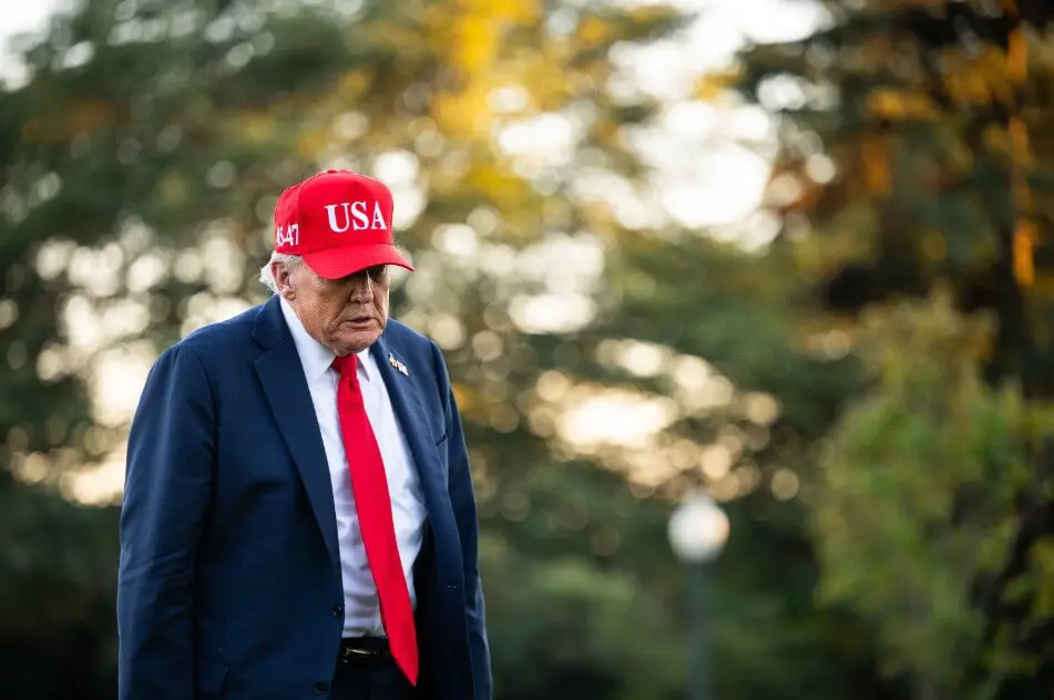 Older man in suit wearing red USA cap