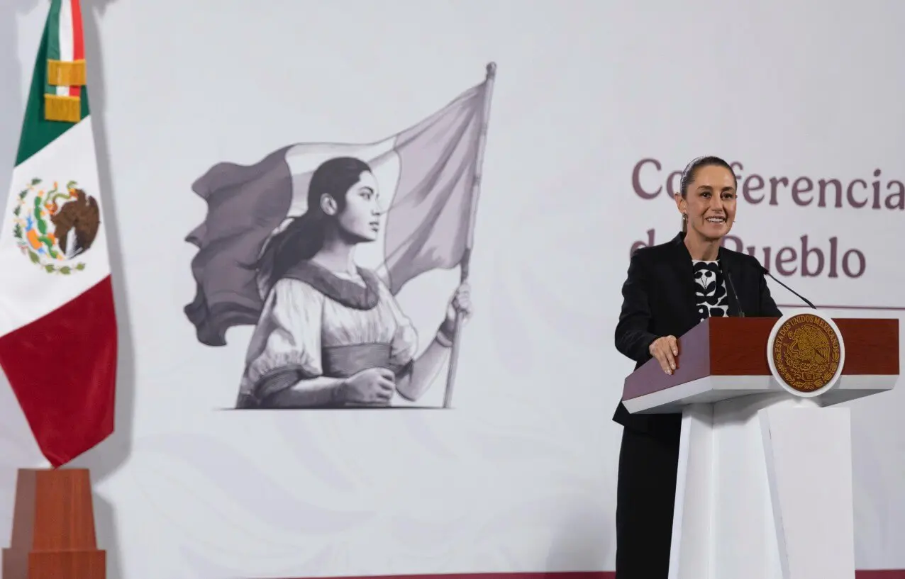 Woman speaking at podium with Mexican flag