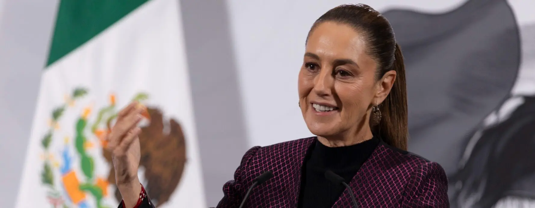 Woman giving speech at podium with flags