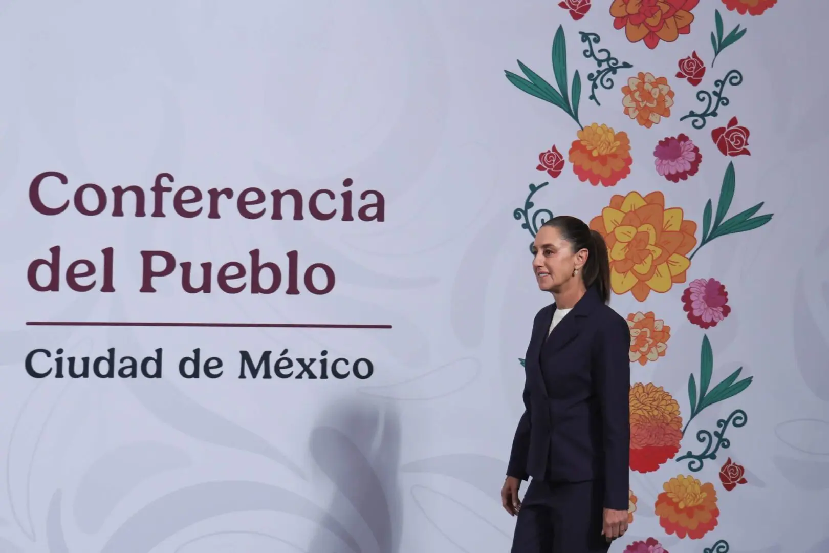 Woman walking past Mexico conference floral backdrop