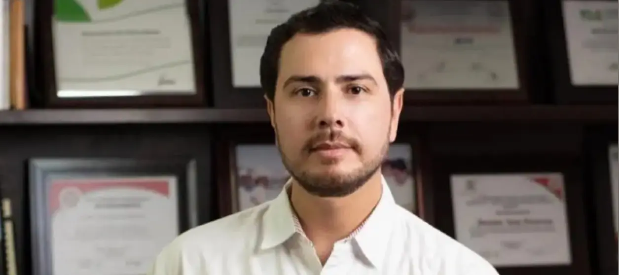 Man in white shirt with certificate-filled background