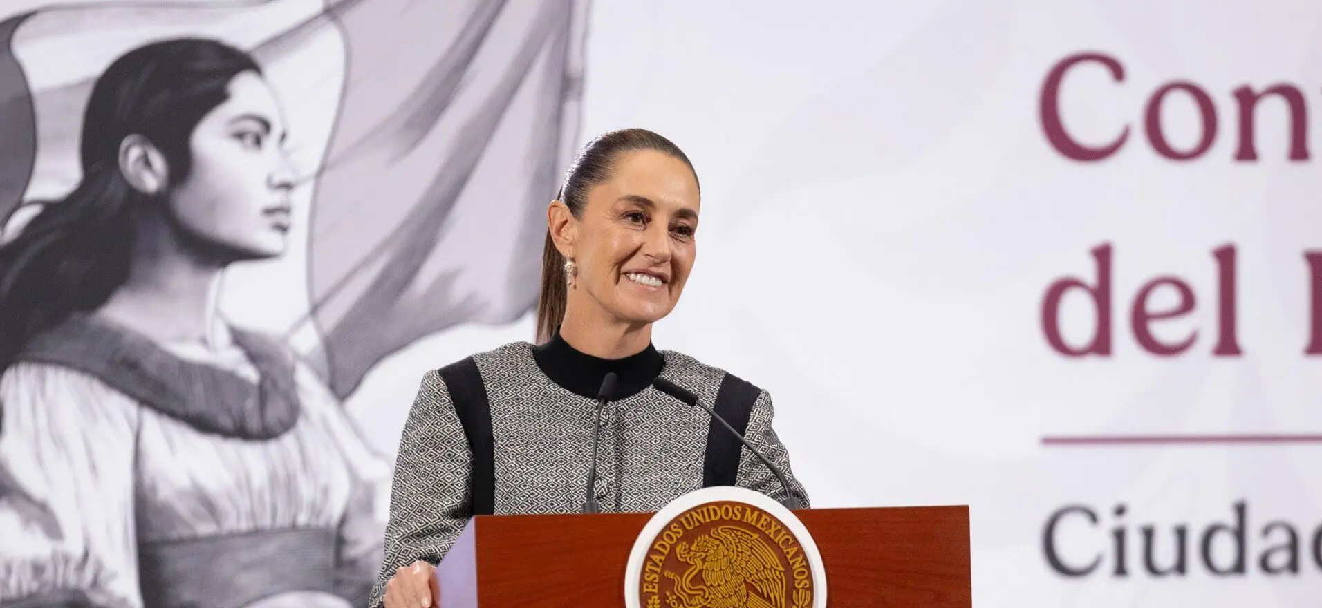 Smiling woman speaking at podium with seal