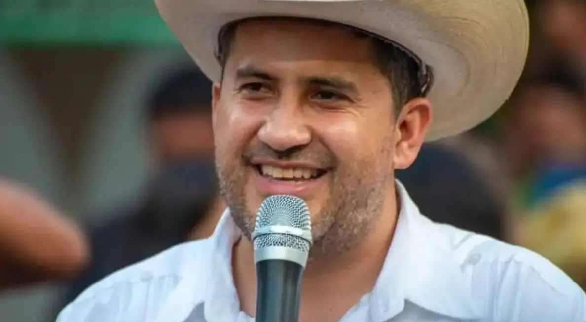 Smiling man in cowboy hat speaking into microphone