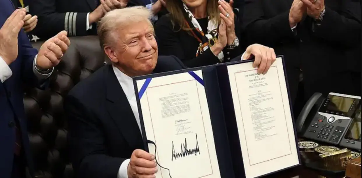 Man displays signed document to applauding crowd