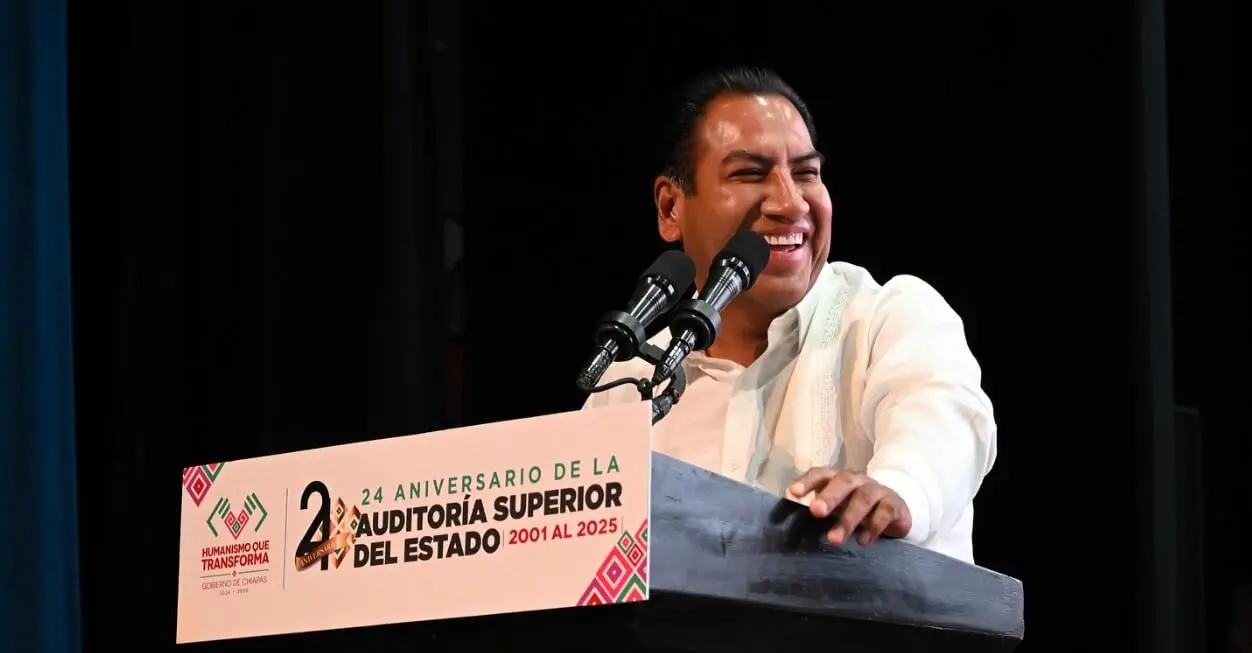 Smiling speaker at podium with anniversary sign