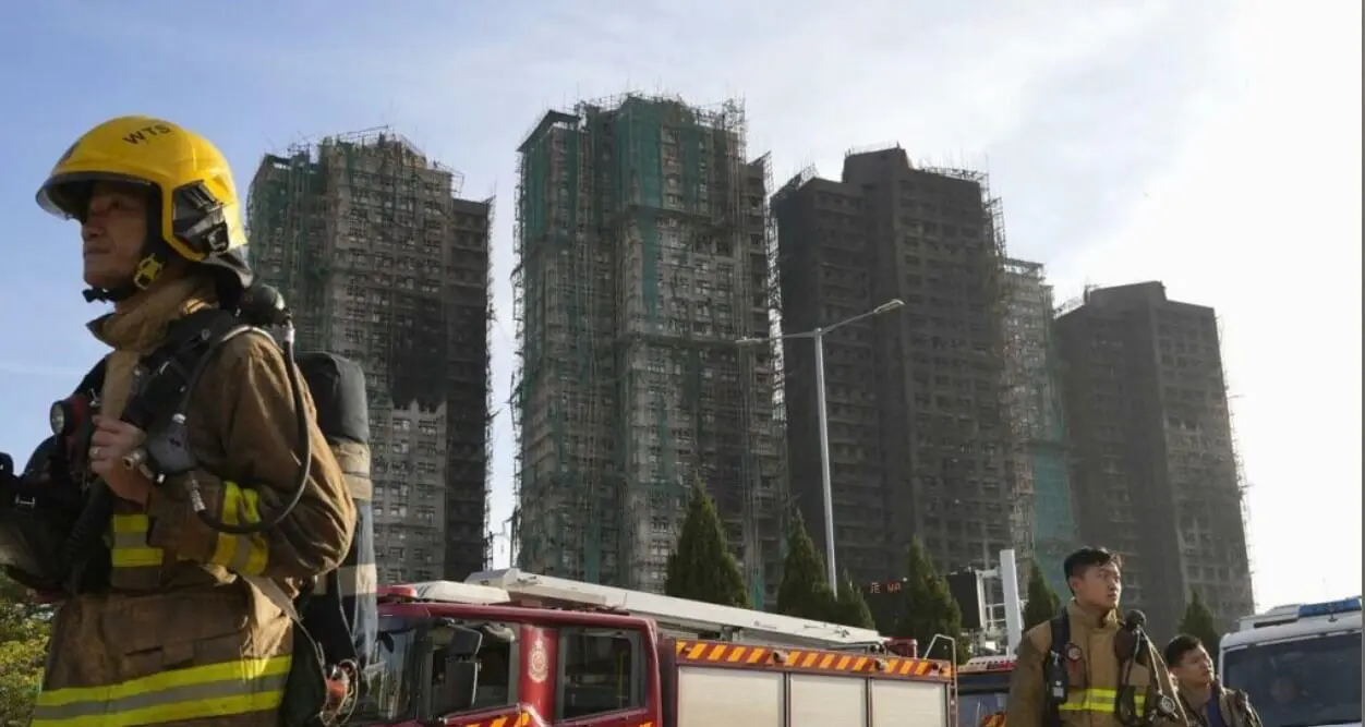 Firefighters with fire truck near scaffolded high-rises