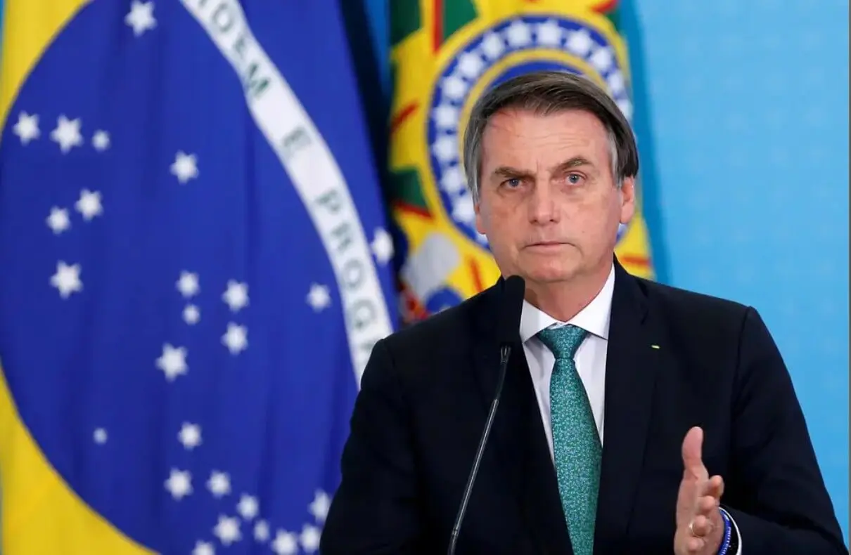 Man speaking at podium with Brazilian flags