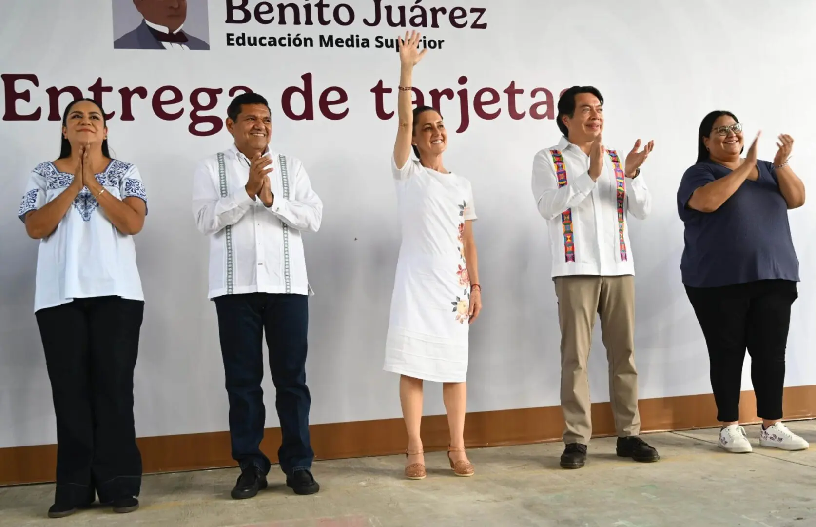 Officials applauding, woman waving on stage
