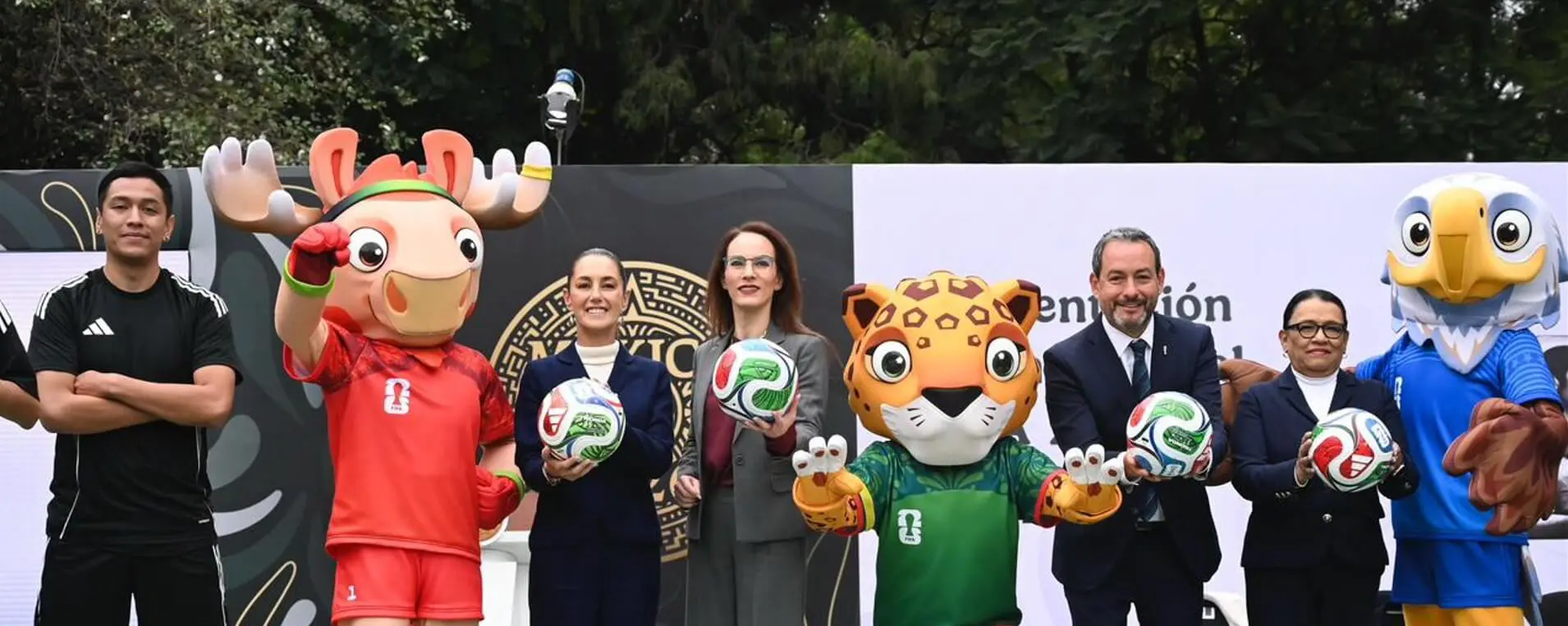 Mascots and officials smiling with soccer balls