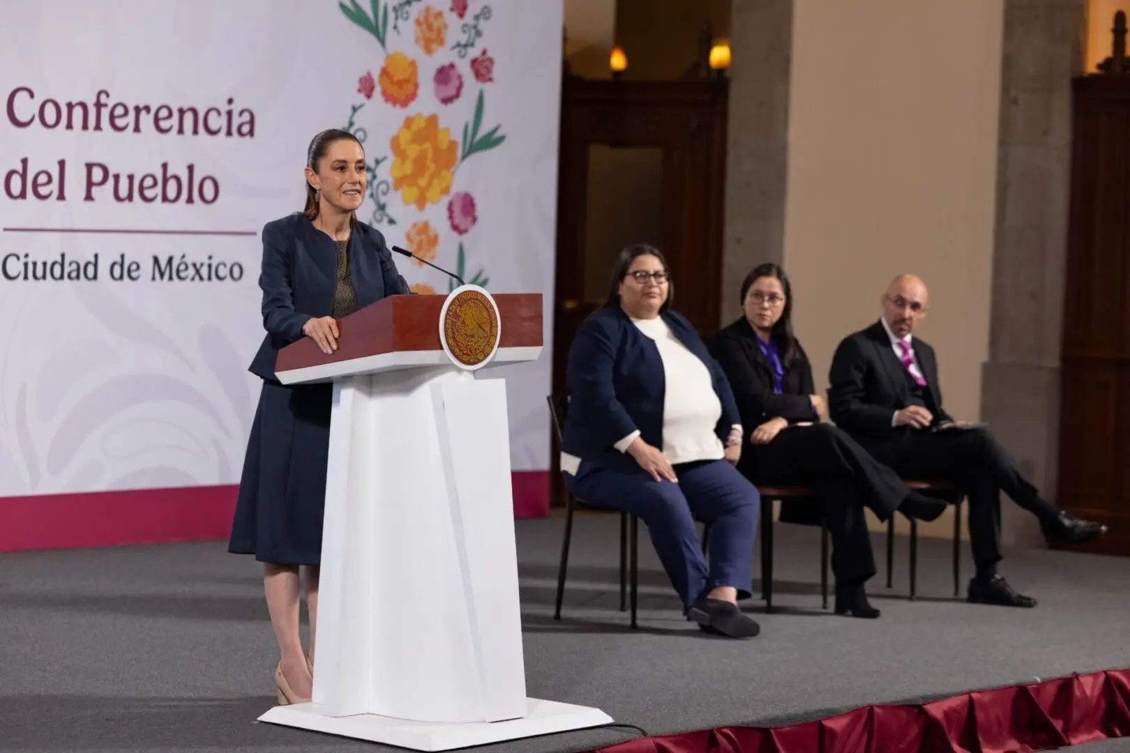Woman speaking at podium with seated panelists