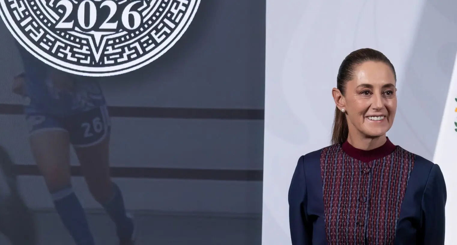 Smiling woman standing beside 2026 emblem