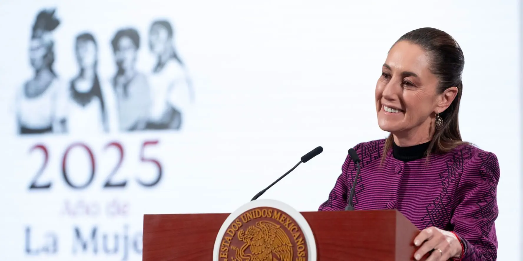 Woman speaking at Mexican podium with 2025 backdrop