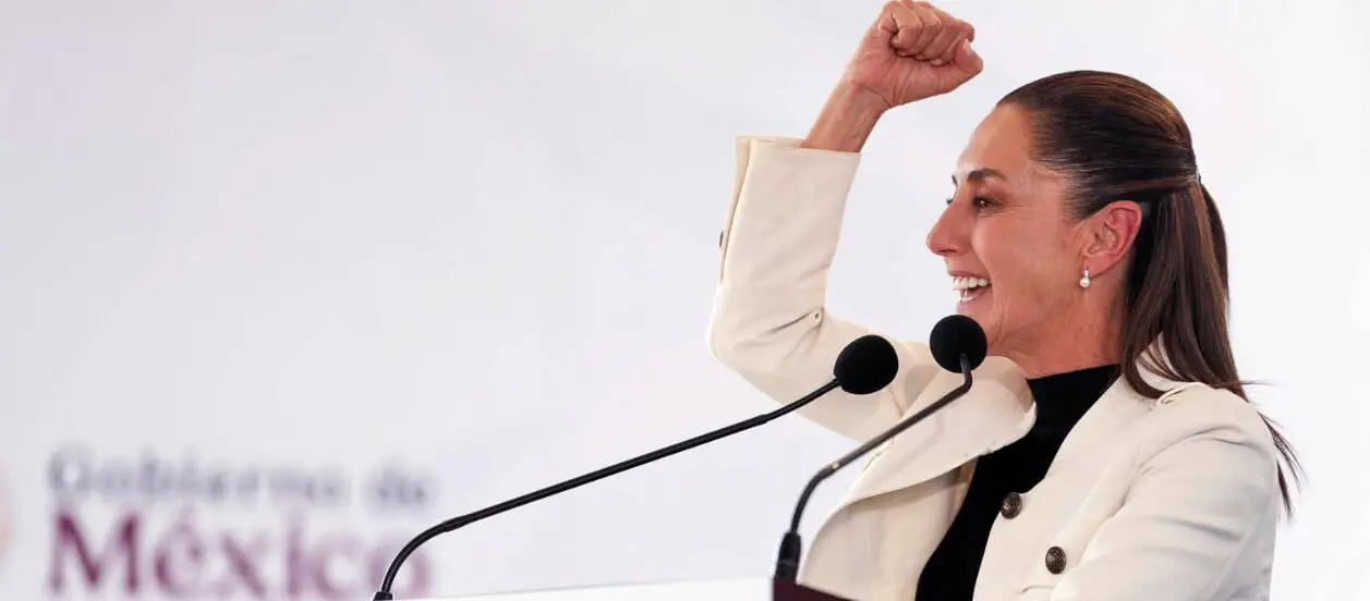 Woman speaker at podium raising triumphant fist