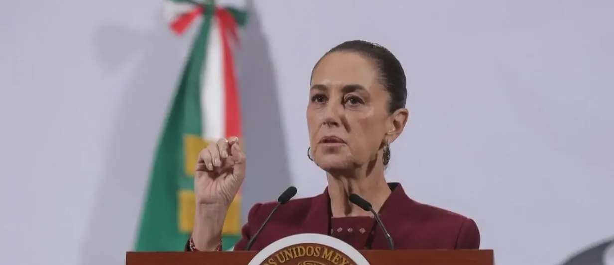Woman politician speaking at podium with Mexican flag