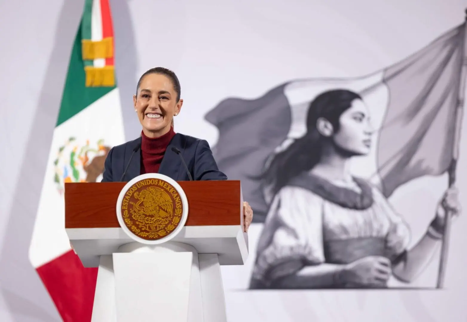 Smiling speaker at podium with Mexican flag
