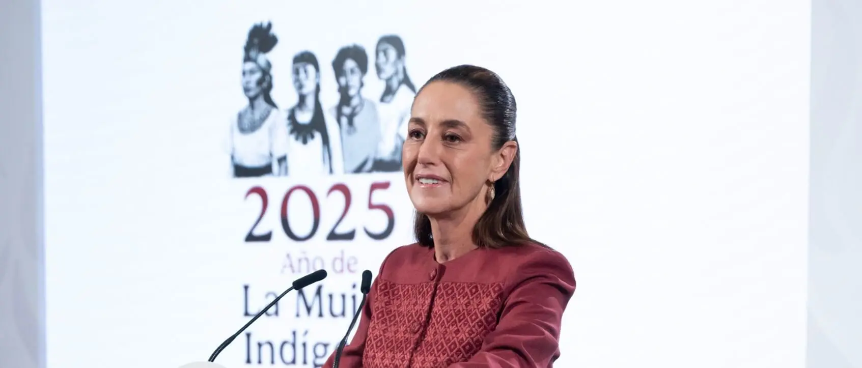 Woman at podium with 2025 indigenous backdrop