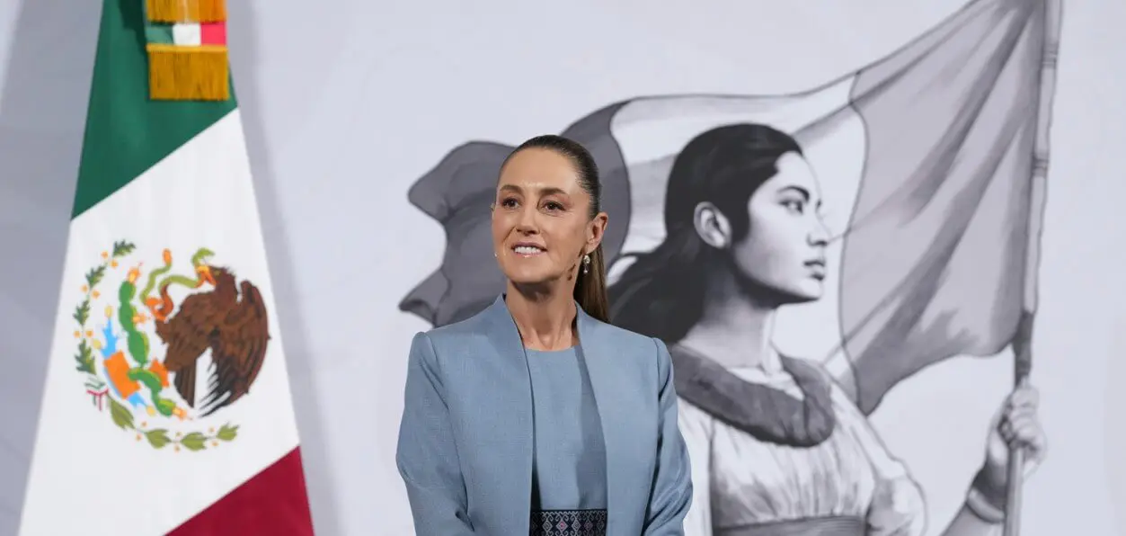 Woman in blue suit before Mexican flag mural