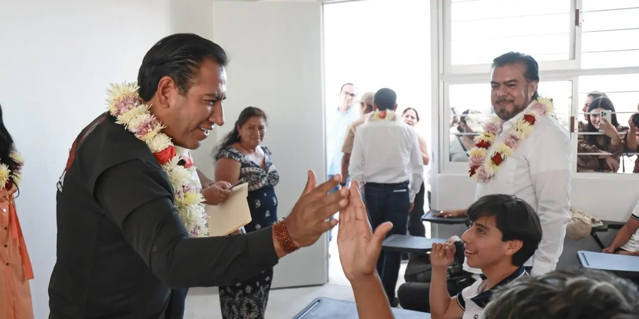 Man with flower garland high-fiving student in classroom