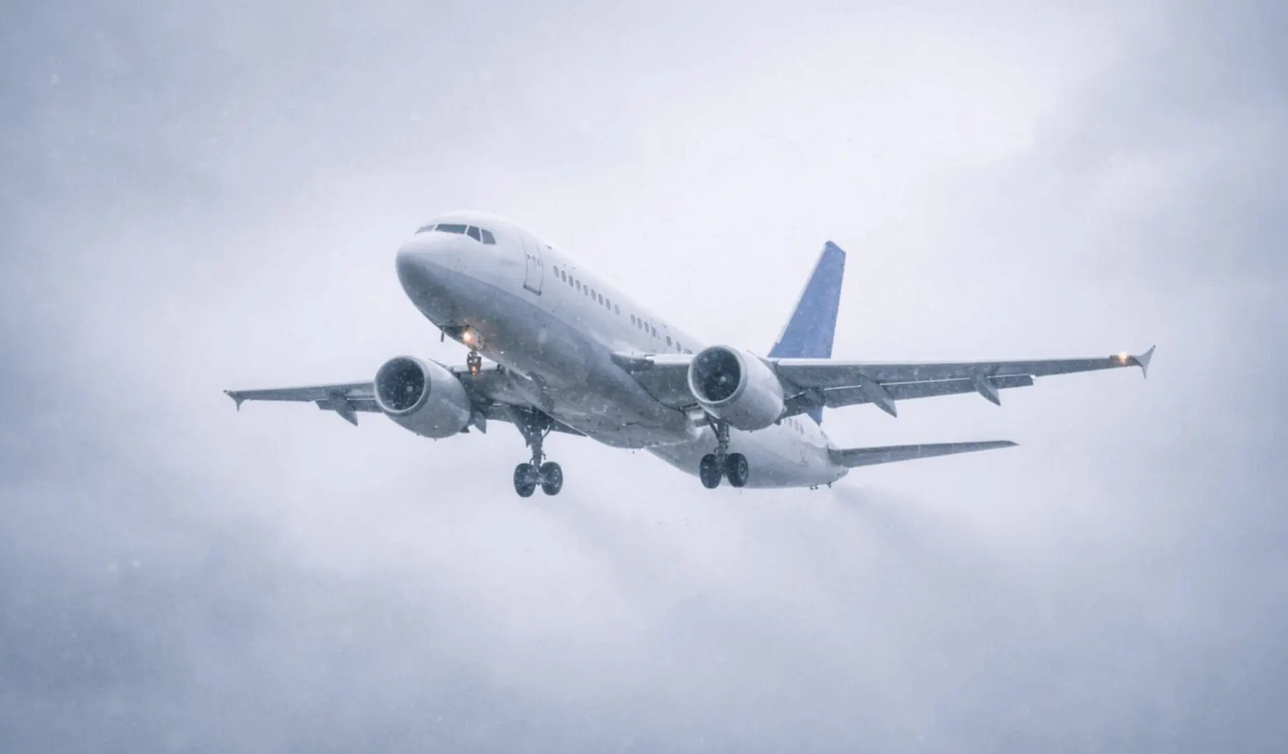 Commercial jetliner approaching through cloudy snowy sky