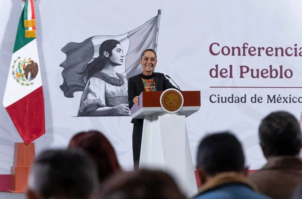 Woman speaking at conference podium with Mexican flag