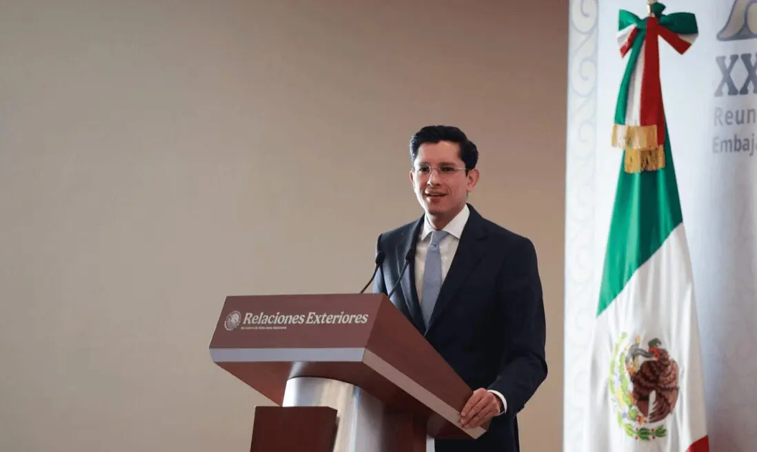 Man at podium with Mexican flag