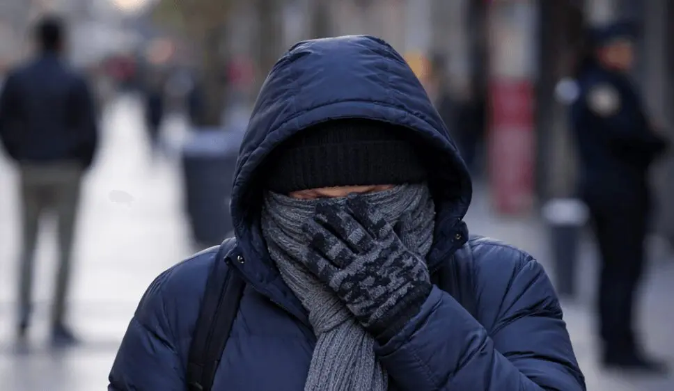 Frío extremo obliga a un hombre a cubrirse el rostro en una calle urbana