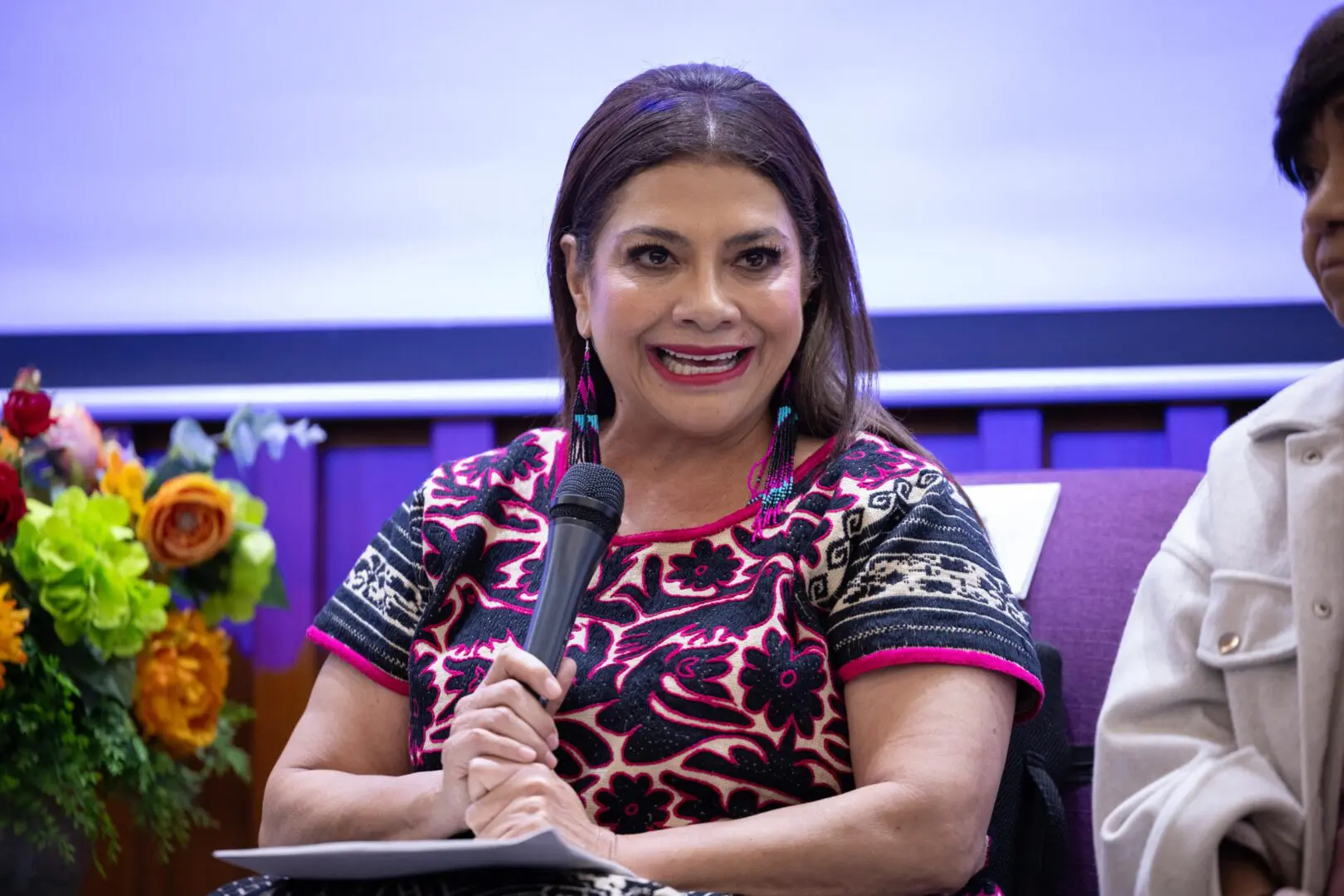 Política hablando con micrófono en conferencia.