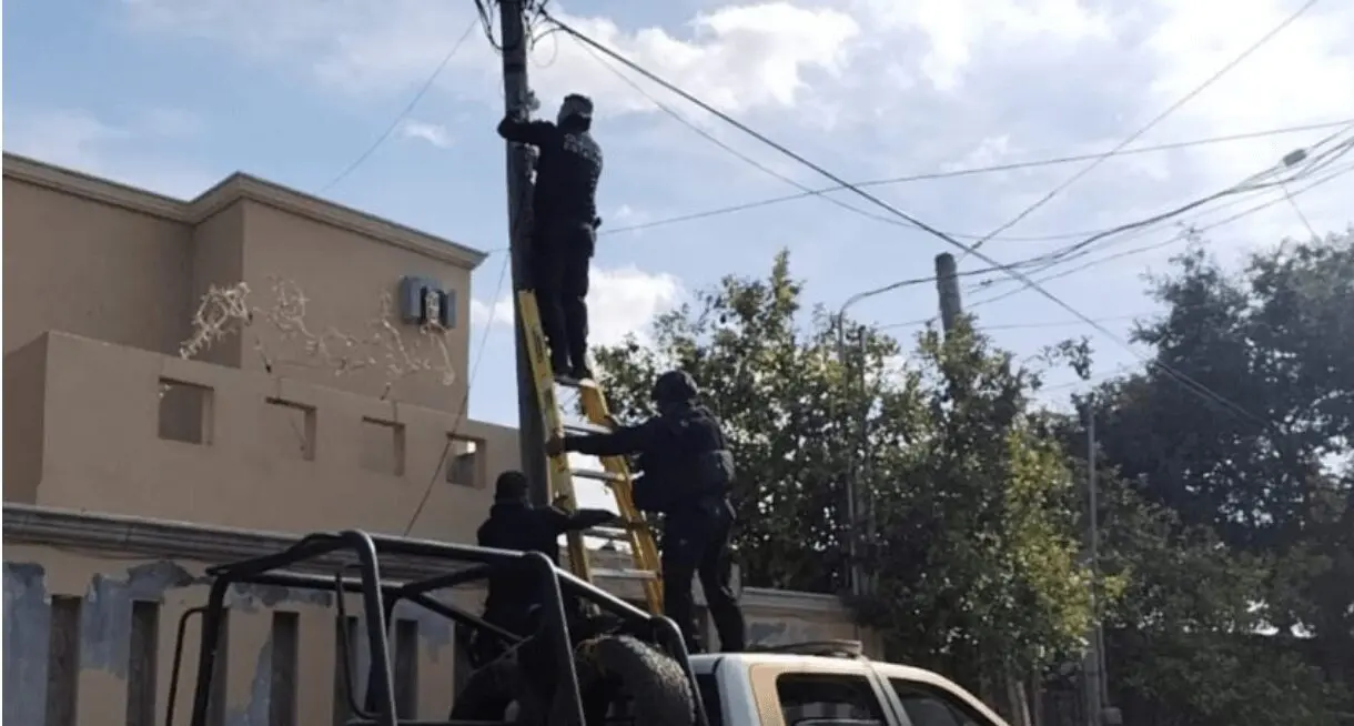 Uniformed officers on ladder at utility pole