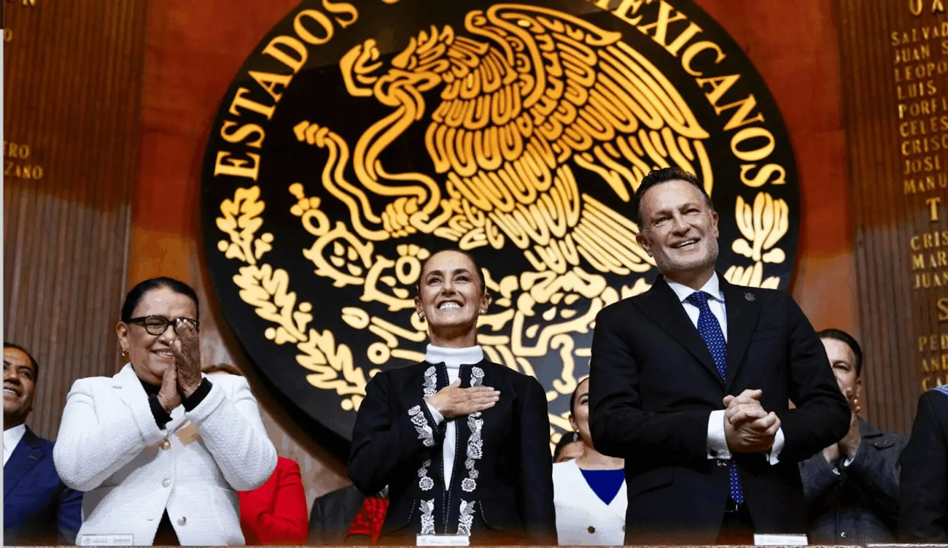 Officials clapping before Mexican national emblem
