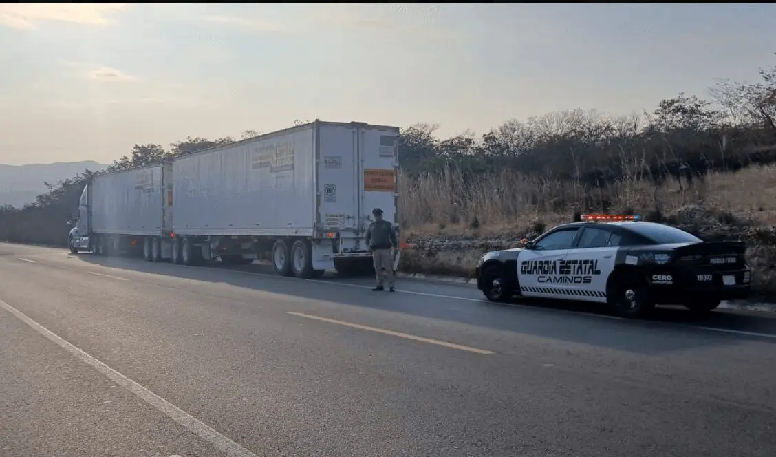 State patrol cruiser parked beside stopped semi-trailers