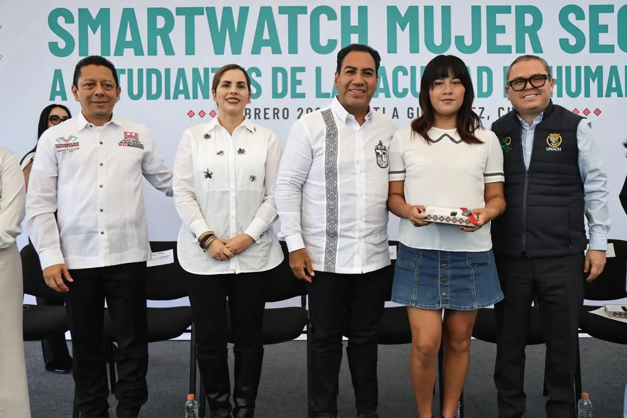 Grupo de personas en evento público. Mujer sosteniendo en sus manos smart watch.
