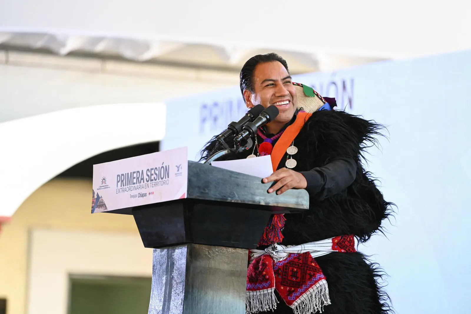 Hombre hablando frente a micrófono en acto público.