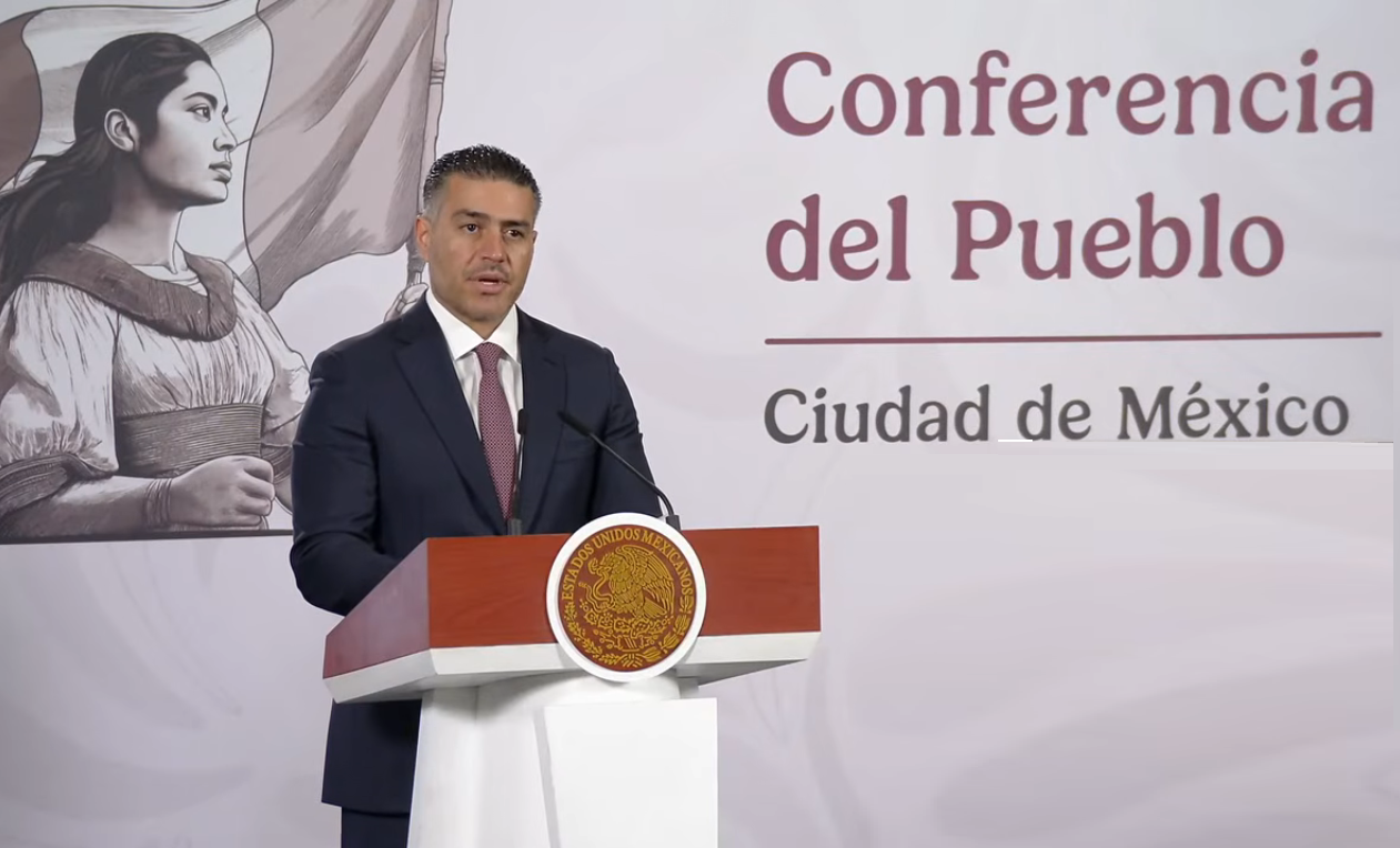 Hombre hablando ante micrófono en conferencia.