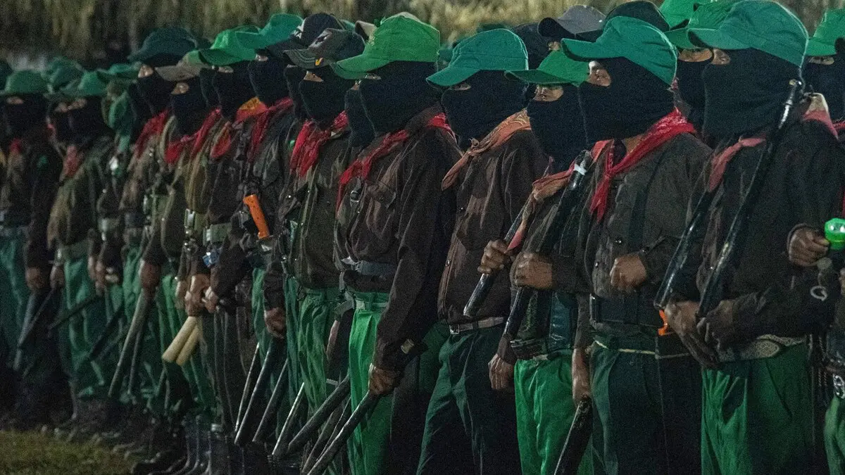 Integrantes del Ejército Zapatista de Liberación Nacional (EZLN) formados con pasamontañas y uniformes verdes durante acto público.