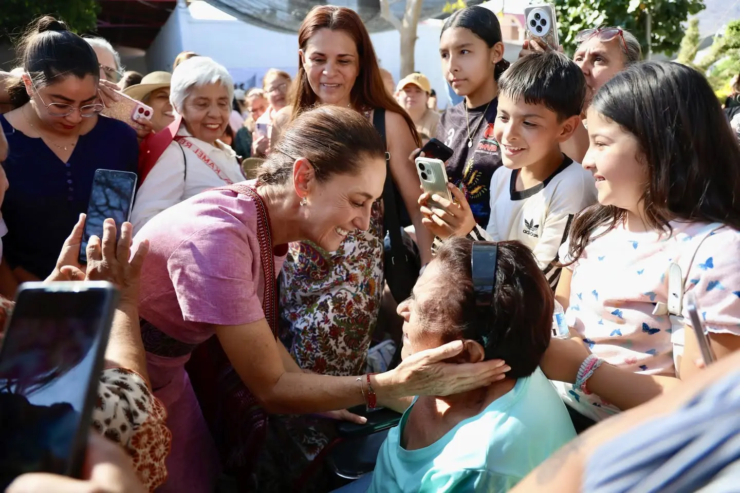 Presidenta de México agarrando con delicadeza mejilla de mujer en Nayarit