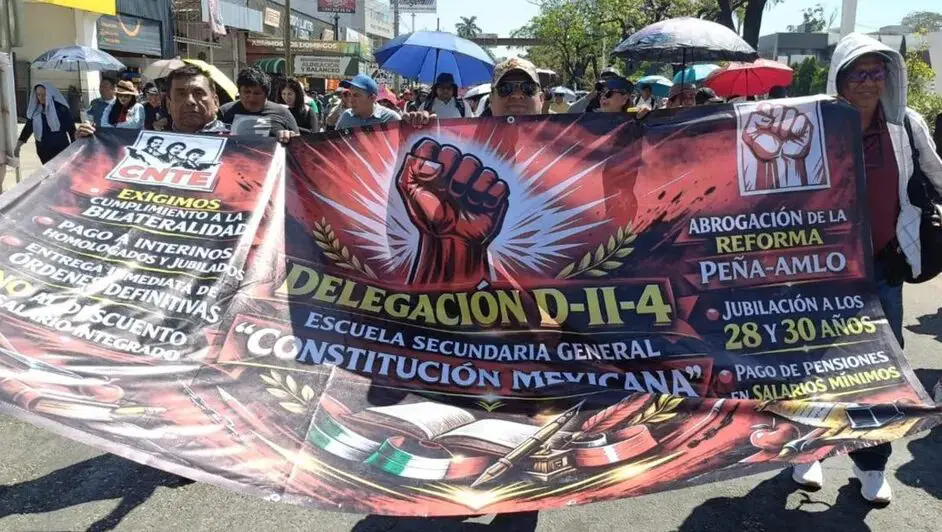 Maestro de la CNTE con pancarta de puño durante protesta.