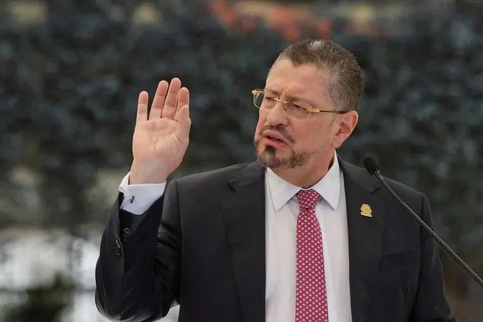 Rodrigo Chaves alza la mano en un evento político.