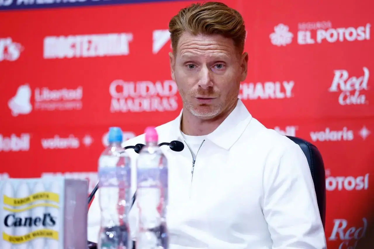 Man in white jacket at red press conference