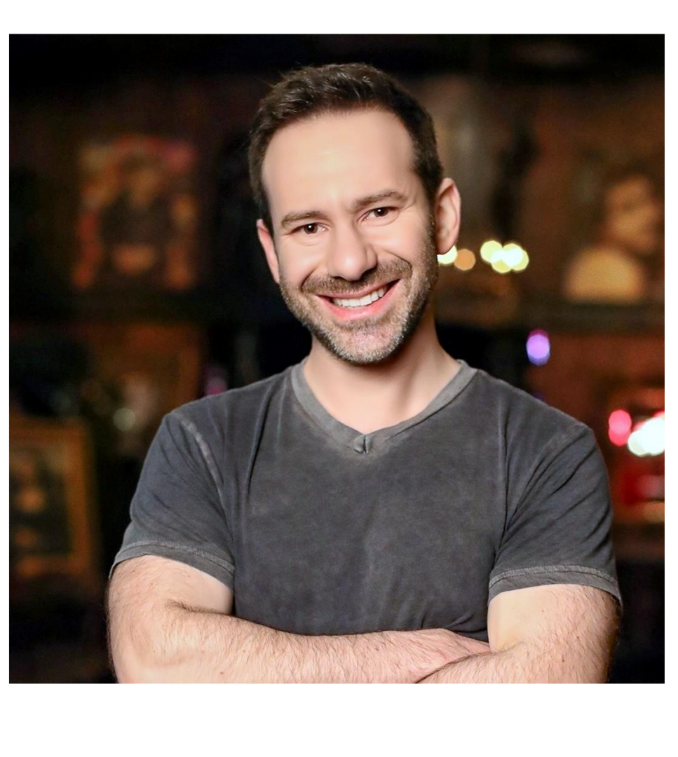 Dueño de OnlyFans de brazos cruzados sonriendo con fondo borroso