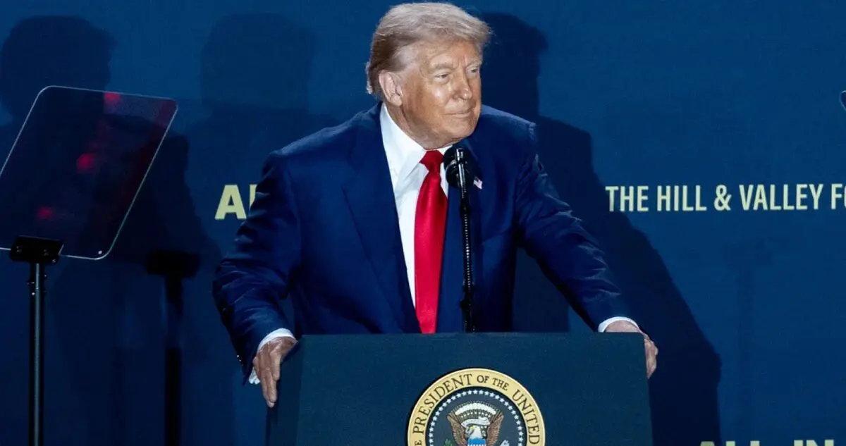 Donald Trump recargando sus manos ante micrófono en evento público