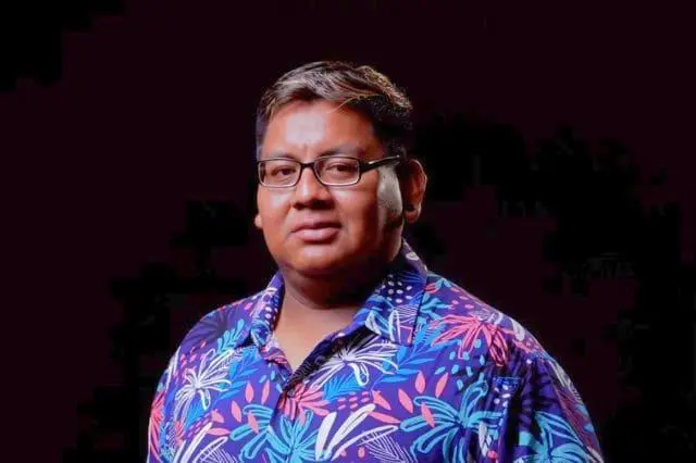 Periodista oaxaqueño con camiseta florida en fondo negro