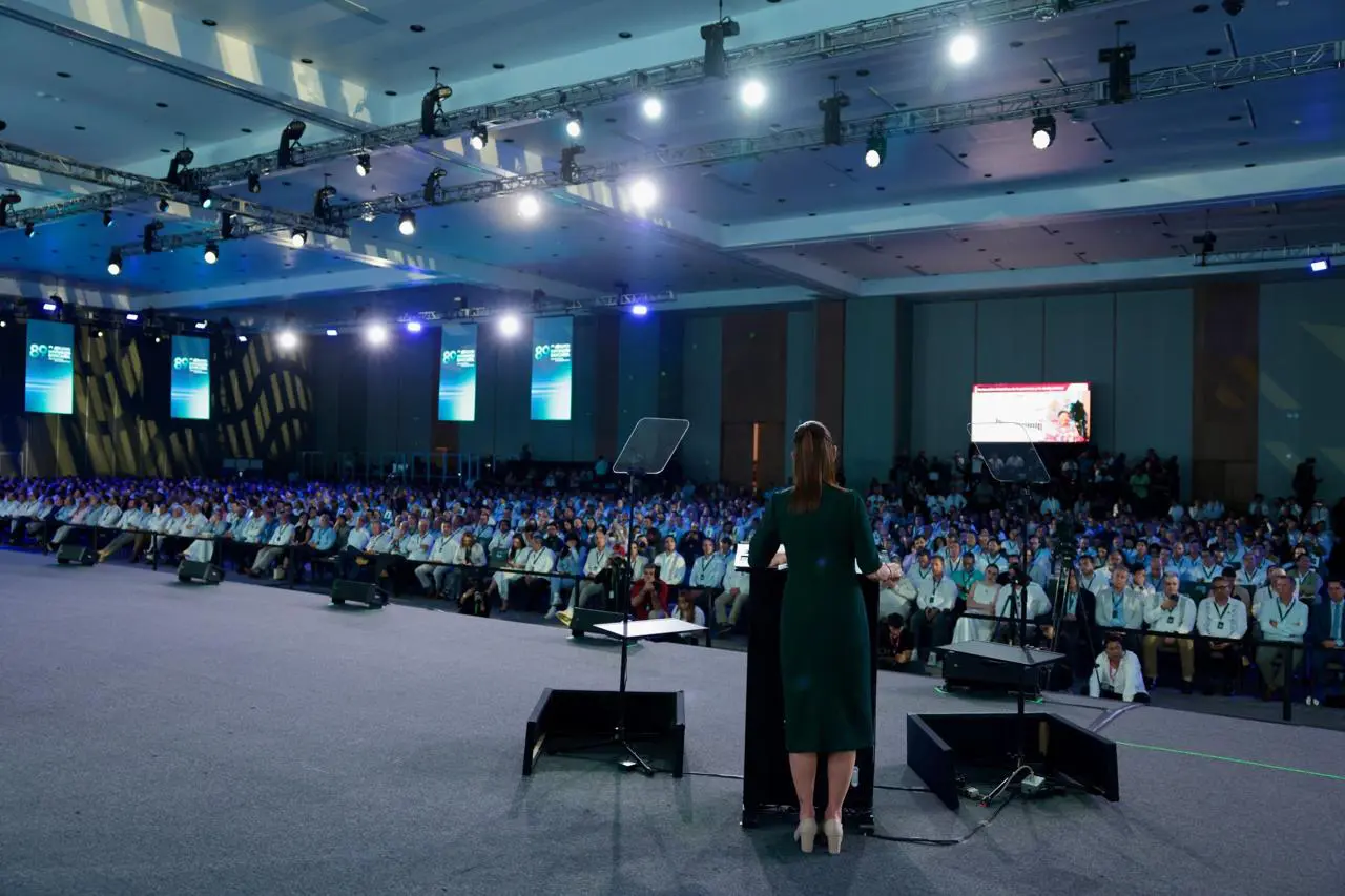 Sheinbaum de espaldas en foro banquero con luces en el techo