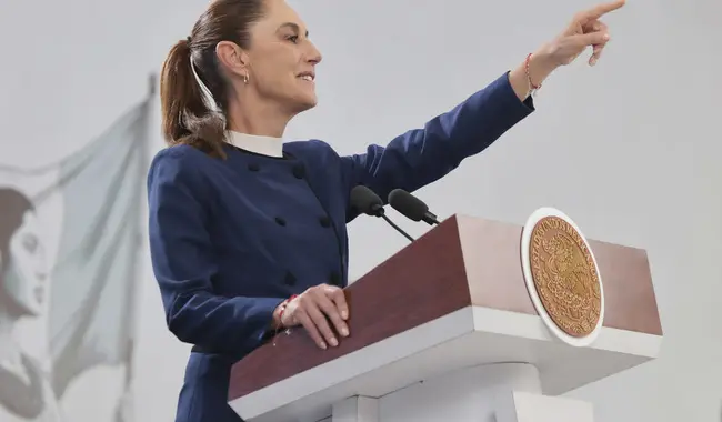 Presidenta de México con el brazo estirado en conferencia de prensa.