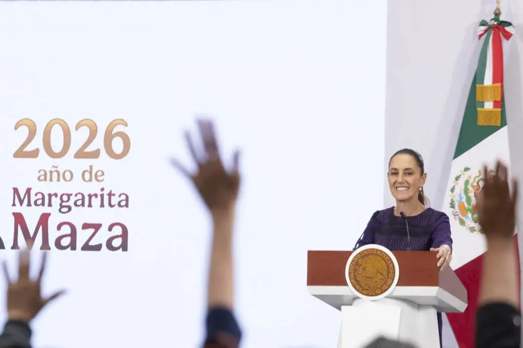 Woman speaking at podium, audience raising hands