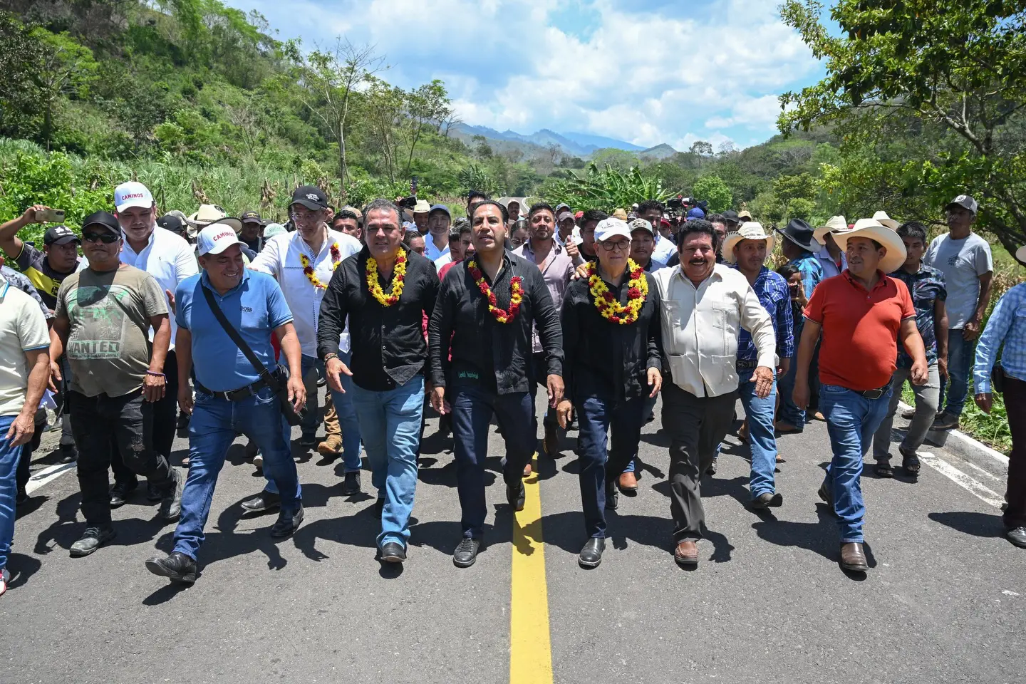 El gobernador de Chiapas caminando sobre carretera junto a funcionarios y pobladores de la región