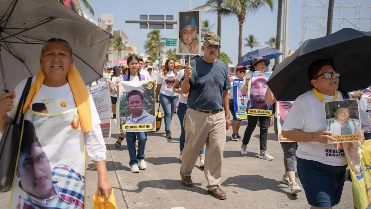 Personas marchan con pancartas con fotos de familiares desaparecidos
