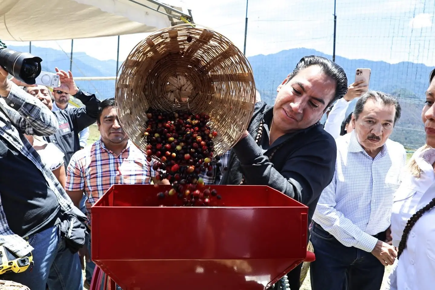 Gobernador de Chiapas con cesto de granos de café virtiéndolos