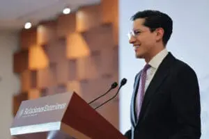 Roberto Velasco sonriendo en el marco de una conferencia frente a micrófono